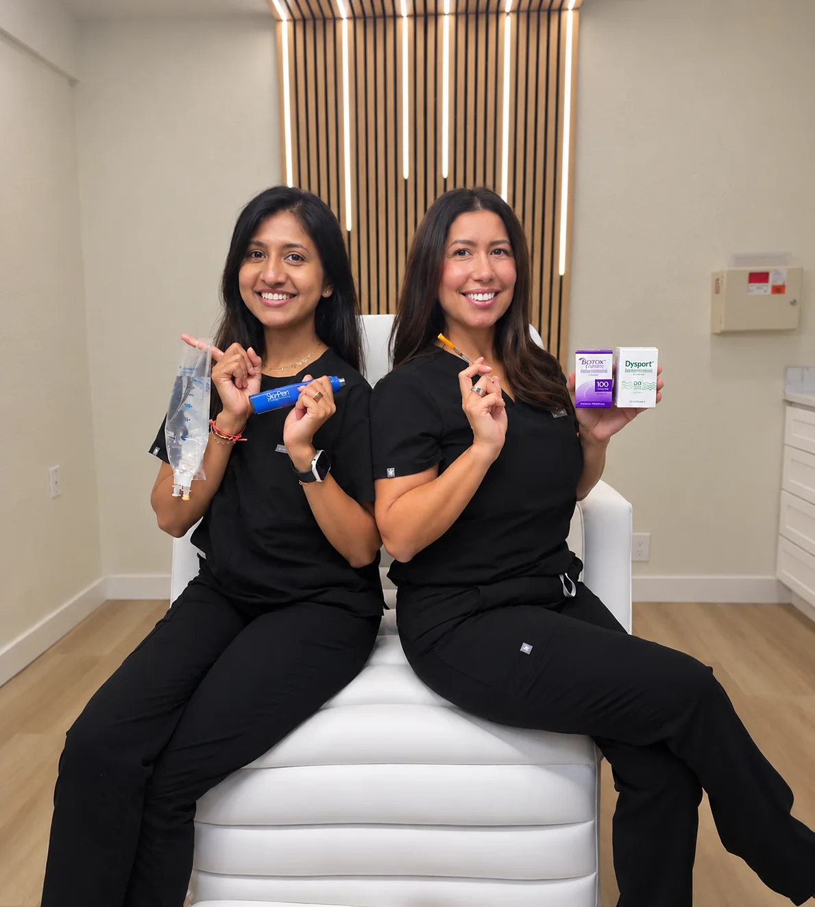 Ria Jivan, BSN, RN holding an IV hydration bag, seated with Kia Brooks, RN